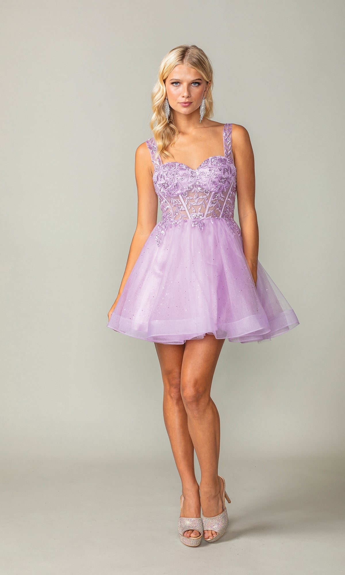 A woman wears the Embroidered-Bodice Short Lace-Up Hoco Dress 3390, a lavender, sleeveless babydoll dress with a fitted bodice and flared skirt. She pairs it with light high heels against a simple background.